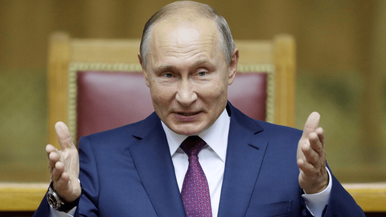 Vladimir Poutine, les deux mains pointées vers l'avant.