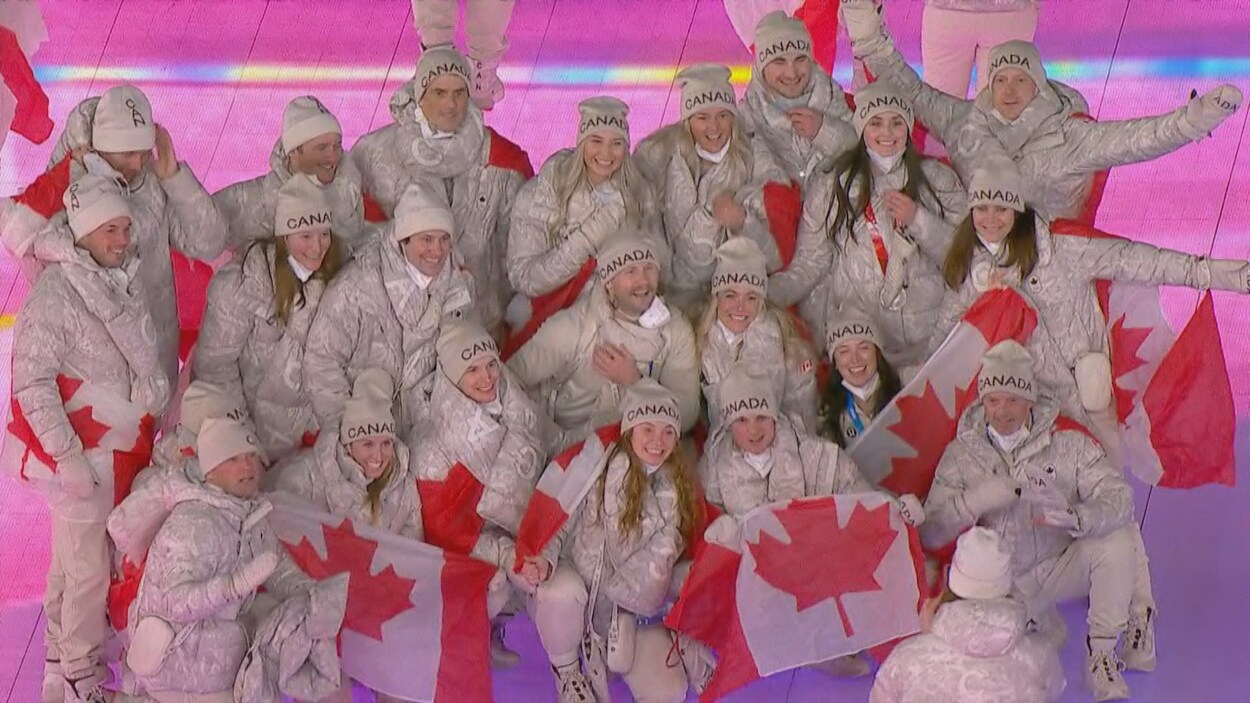 Des athlètes canadiens qui tiennent des drapeaux du Canada.