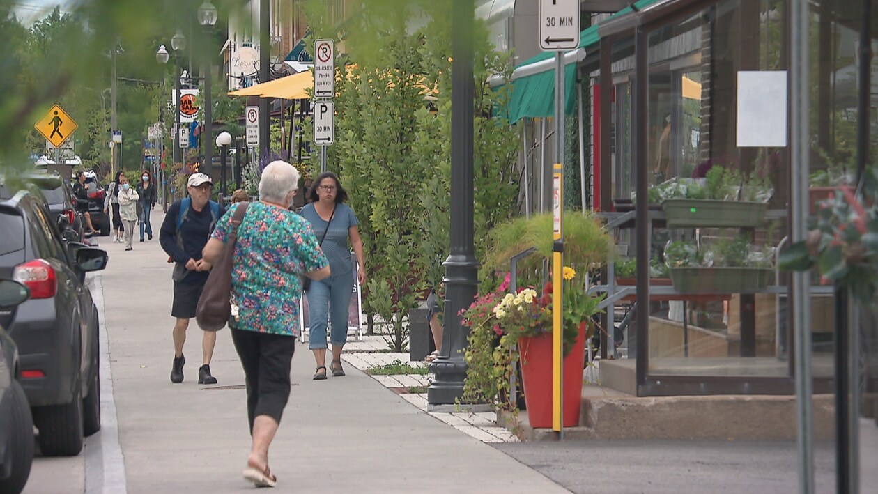 Des passants marchent sur le trottoir de l'avenue Maguire à Québec.  