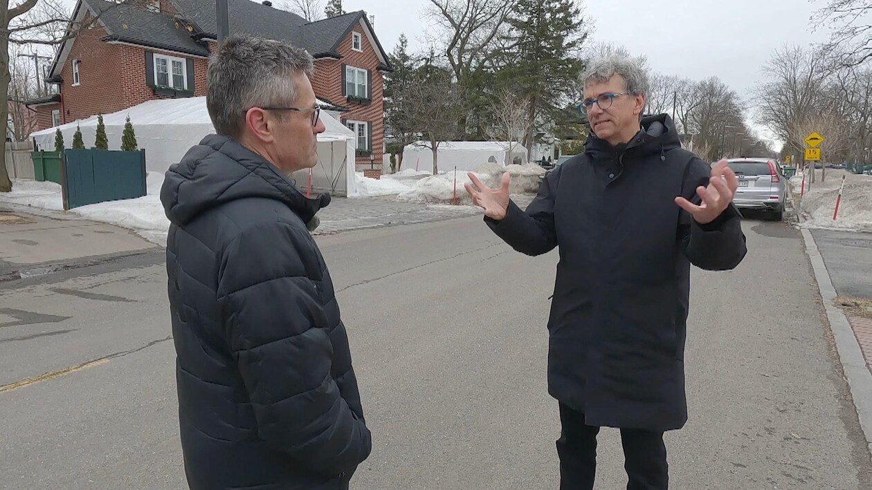 Deux hommes discutent dans un quartier résidentiel, l'hiver. 