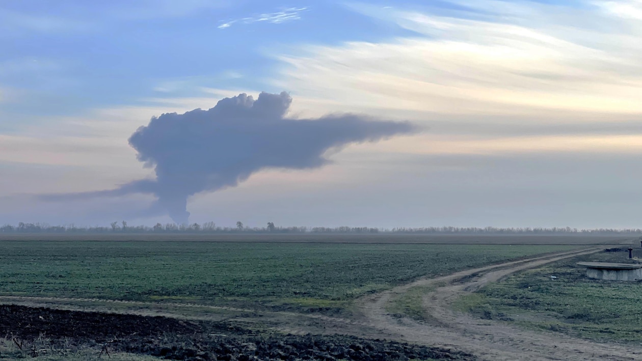 Des terres agricoles et au loin un nuage de fumée provenant d'un bombardement.