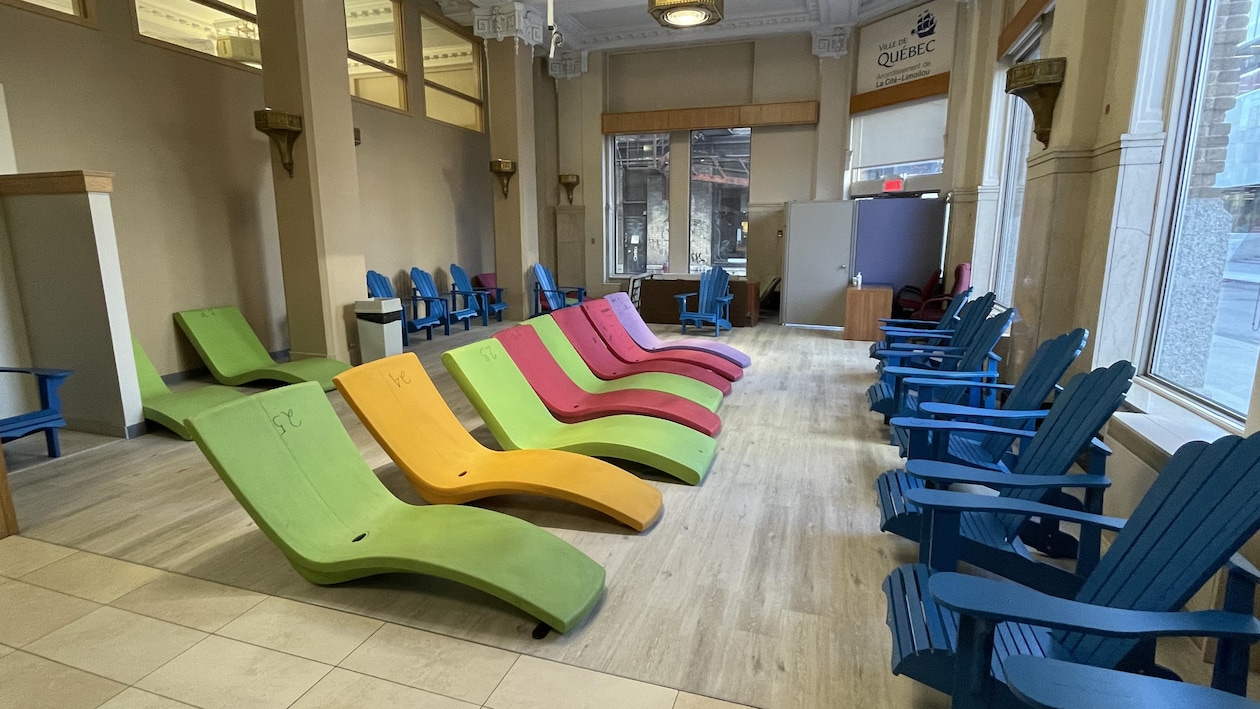Des chaises Adirondacks et des transats en plastique sont placées côte-à-côte dans l'ancienne salle du conseil d'arrondissement.