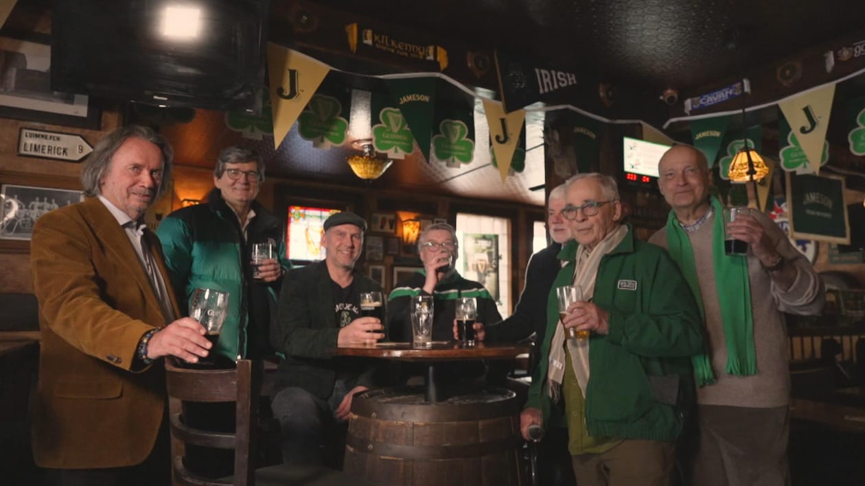 Sept hommes dans un pub irlandais, en train de boire de la bière, autour d'une table.