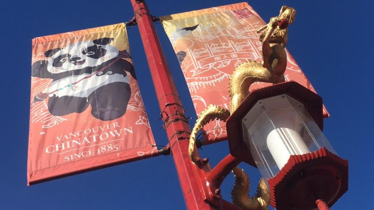 Une affiche sur un lampadaire qui arbore un panda. Il est aussi inscrit Vancouver Chinatown since 1885. Sur la lumière, il y a un dragon doré. 