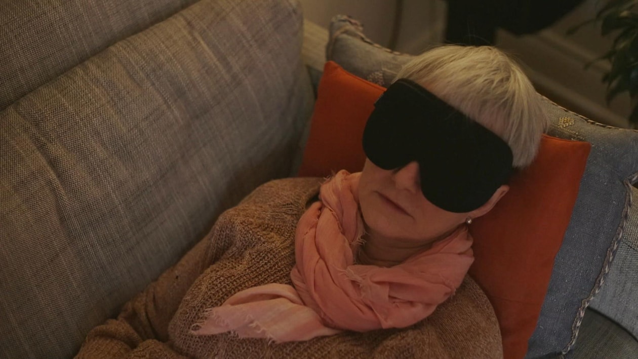 Une patiente couchée sur un divan avec un masque noir sur les yeux.