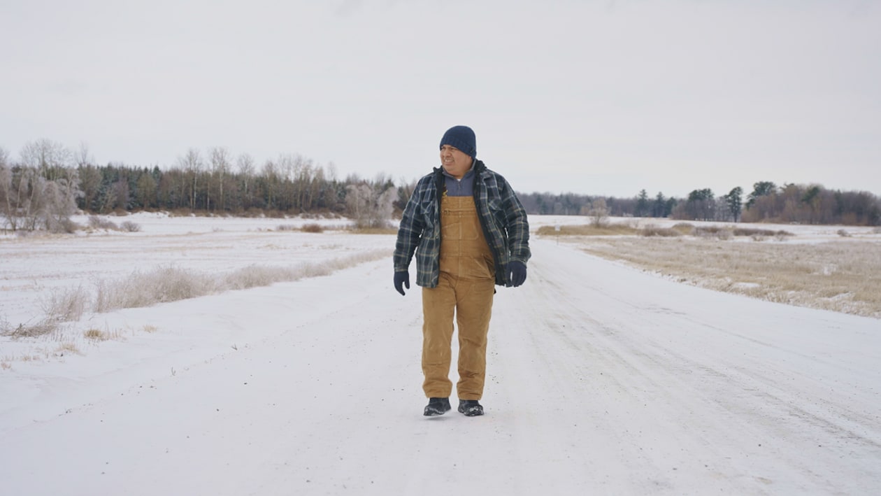 Un homme qui marche sur une route enneigée.