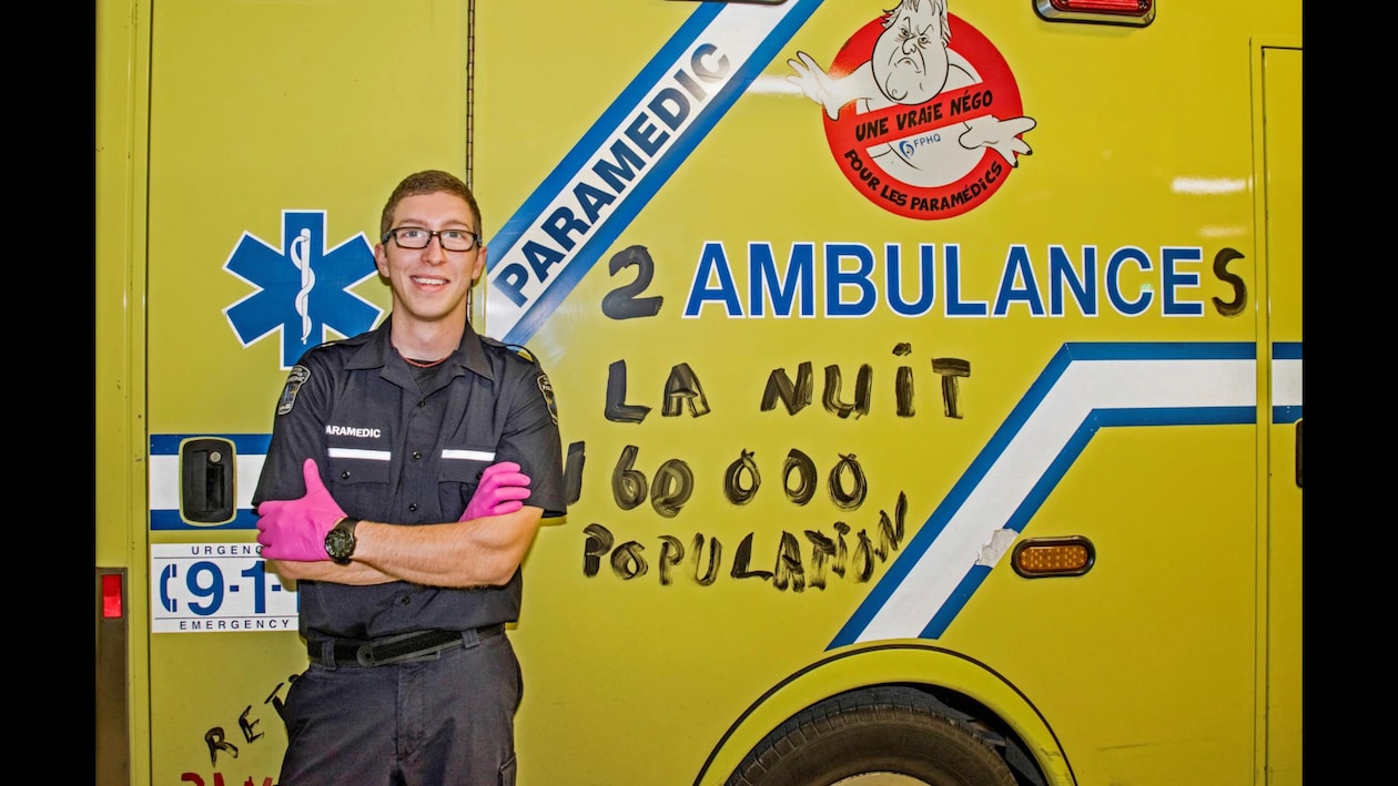 Hugo St-Onge, jeune ambulancier, pose fièrement devant une ambulance.