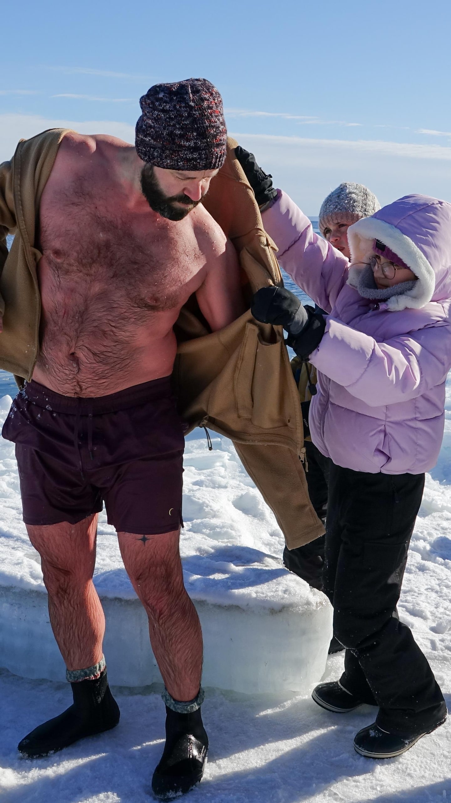 Luc Bourdages remet ses vêtements, aidé de ses enfants, après une baignade nordique.  