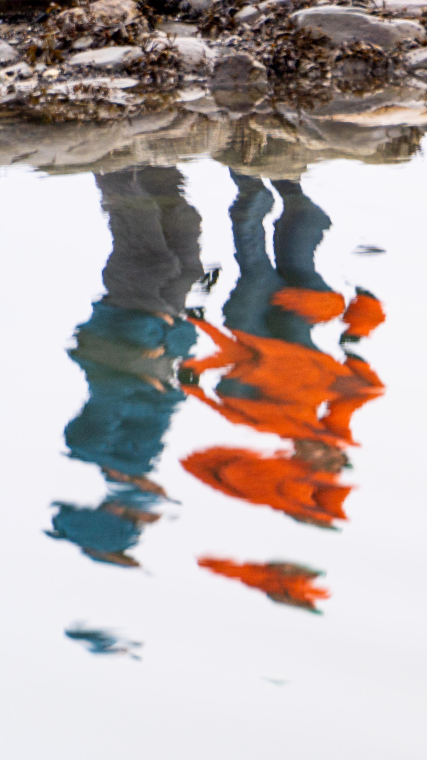 Les silhouettes de quelques personnes sur la rive reflétées dans l’eau