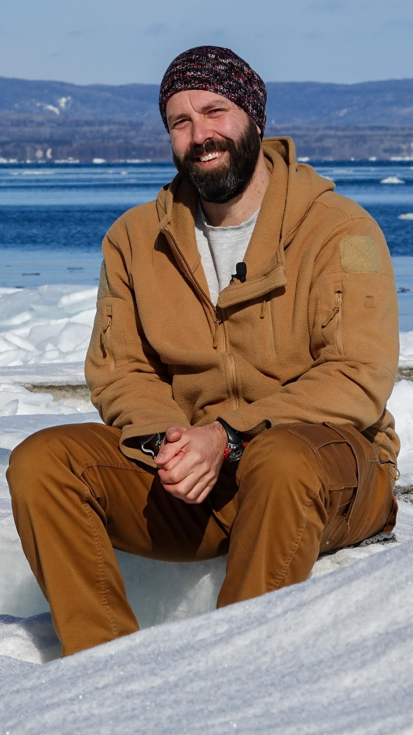Luc Bourdages assis sur des blocs de glace sur une plage de Carleton-sur-Mer.