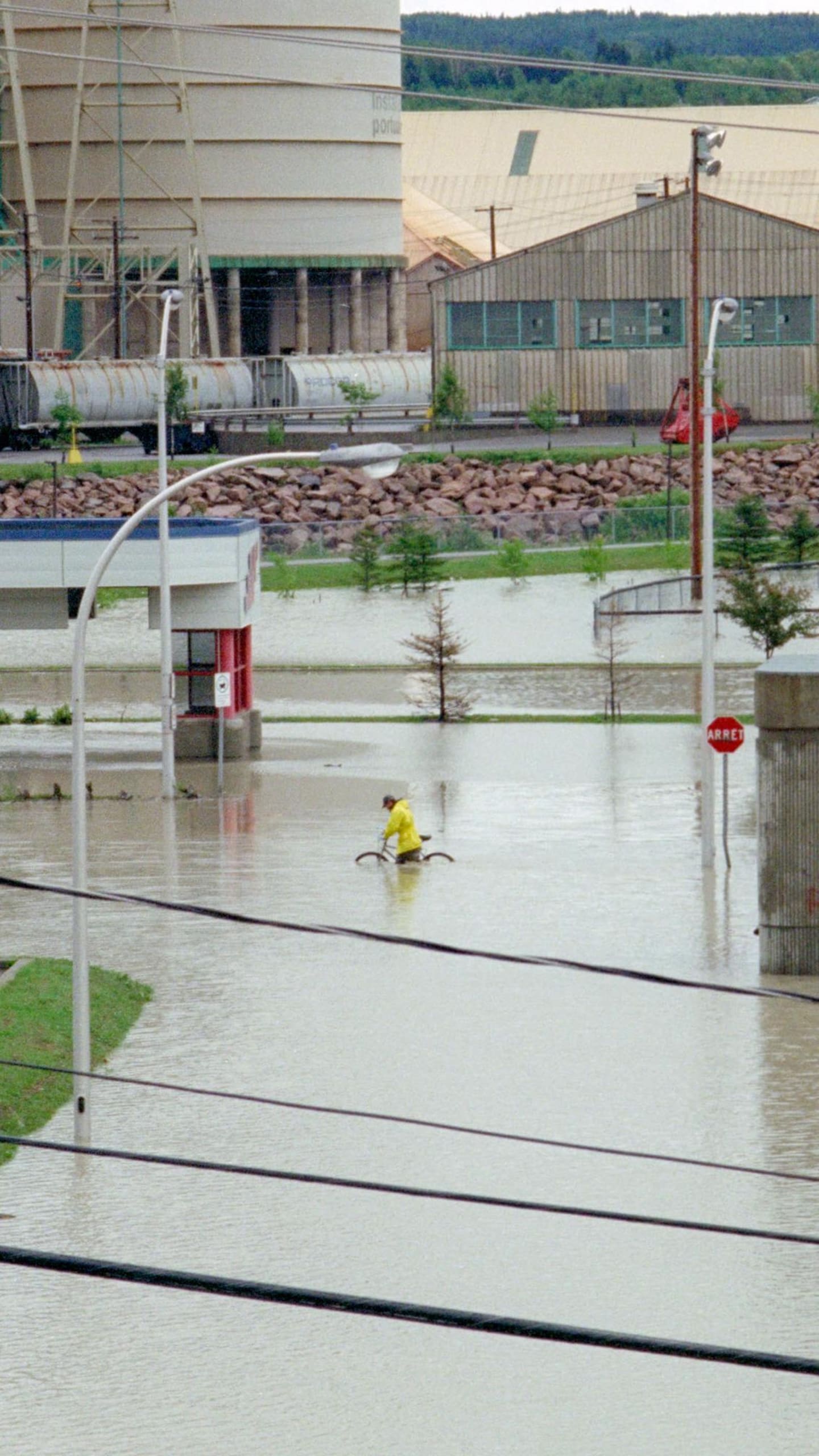 Un cycliste circule sur un terrain inondé près des installations portuaires de La Baie.