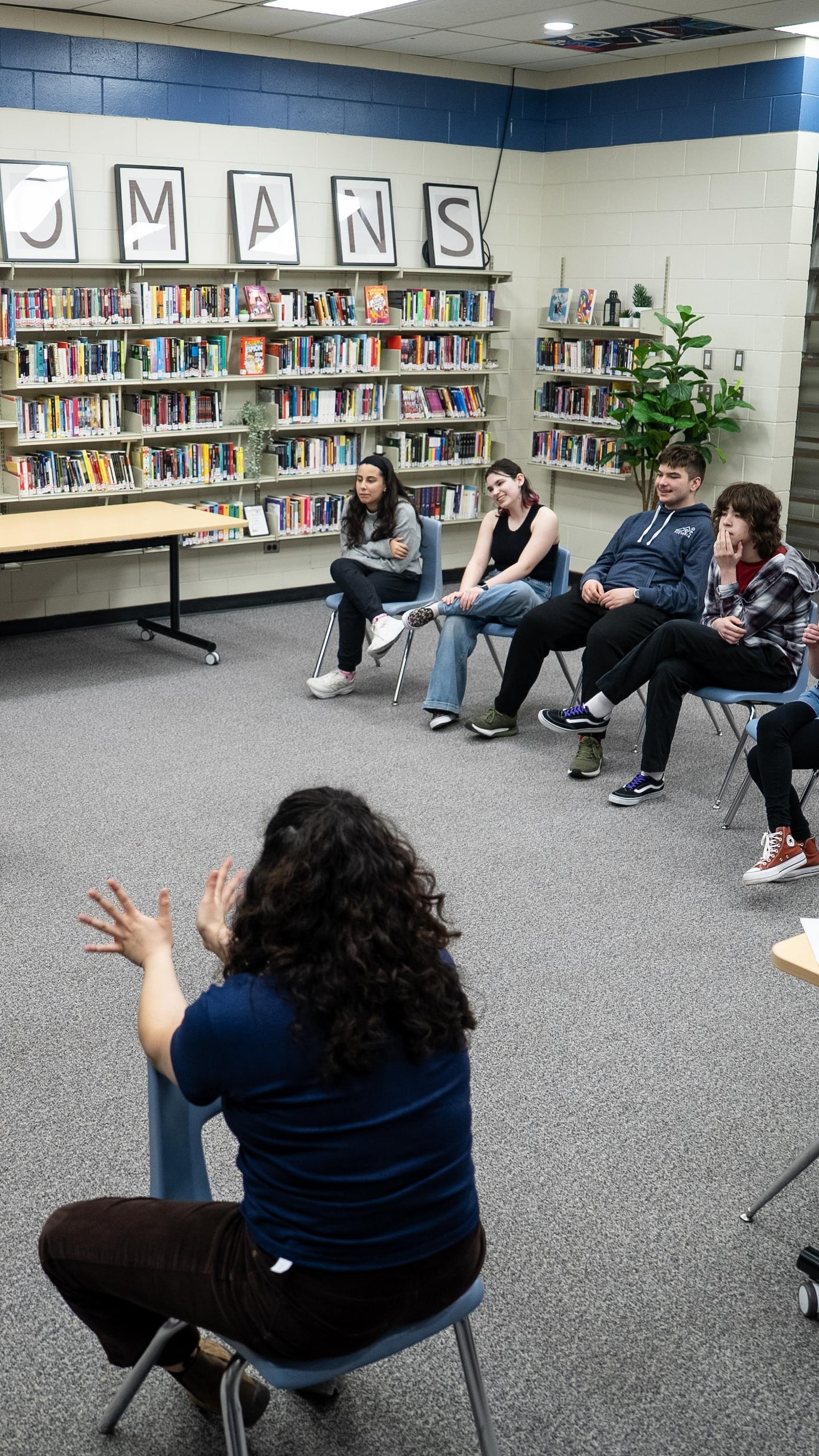 Zara Ramlal observe ses élèves qui pratiquent des improvisations au milieu des étagères de livres.