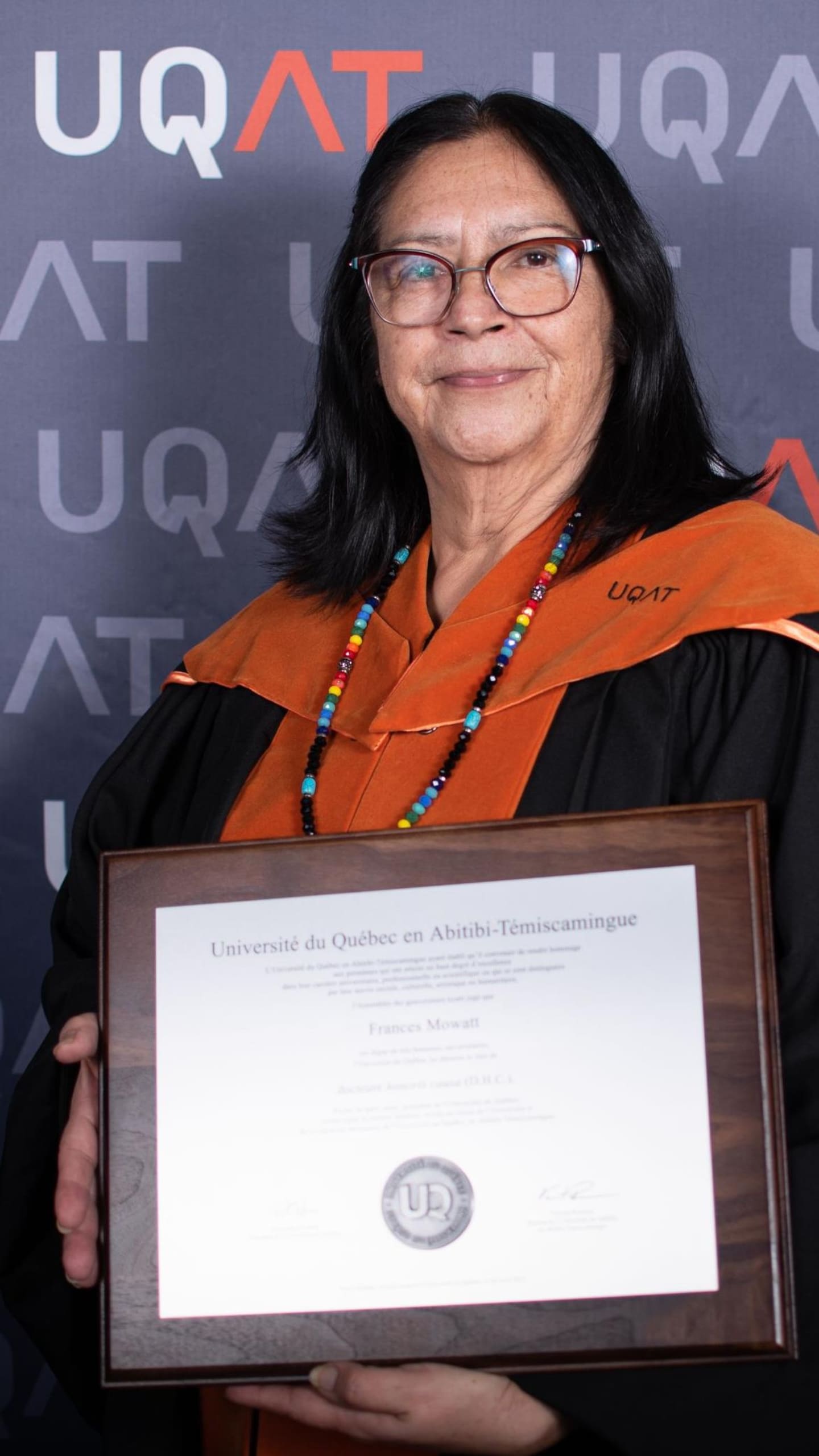 Frances Mowatt pose avec son doctorat honoris causa de l’Université du Québec en Abitibi-Témiscamingue.