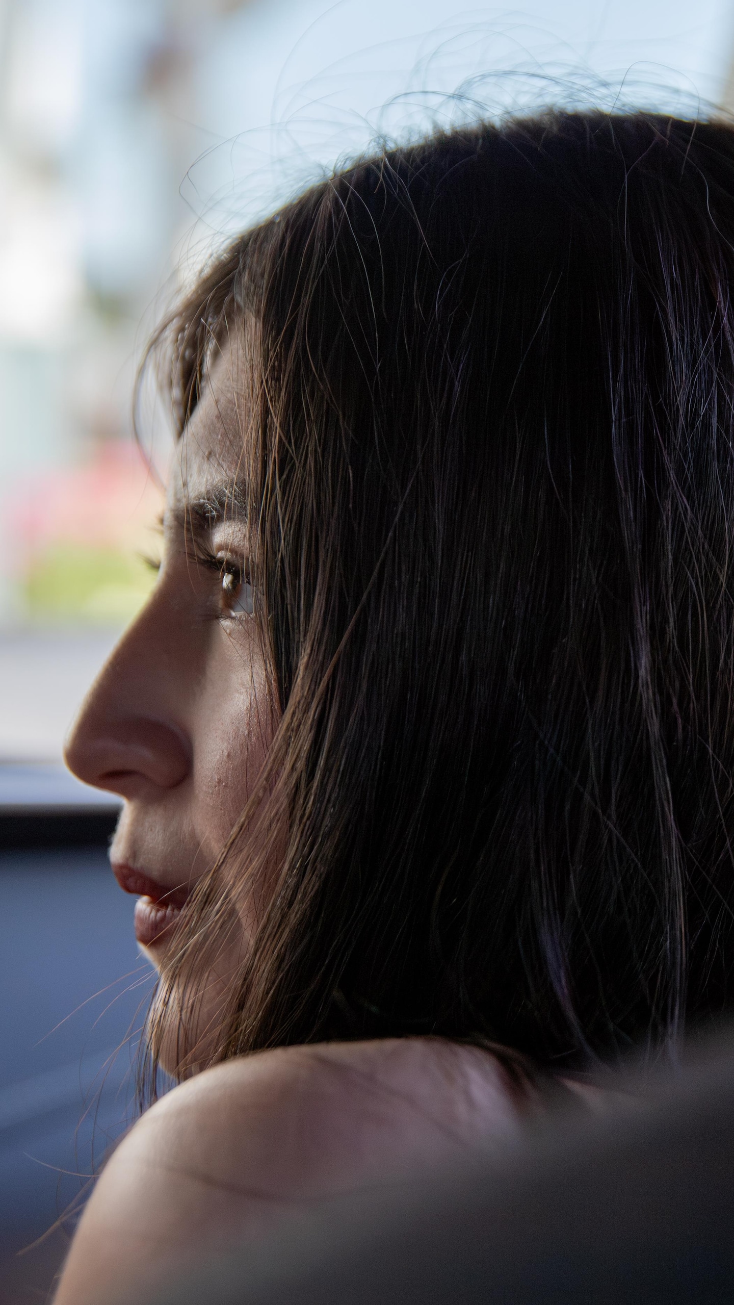 Une jeune femme, vue depuis le siège arrière, regarde de profil vers l’avant d’une voiture.