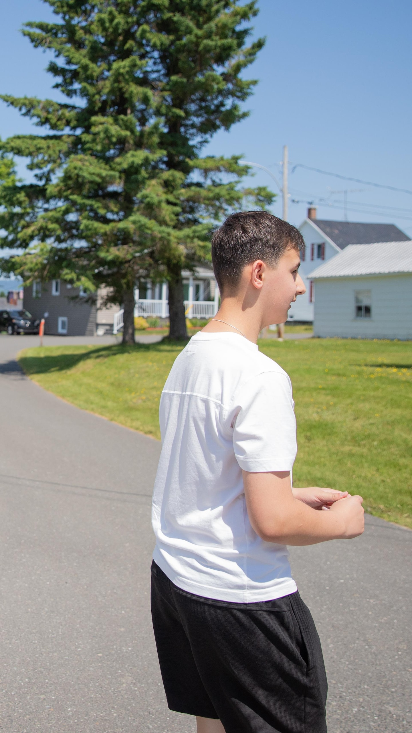 Un jeune homme marche dans une rue bordée de maisons.