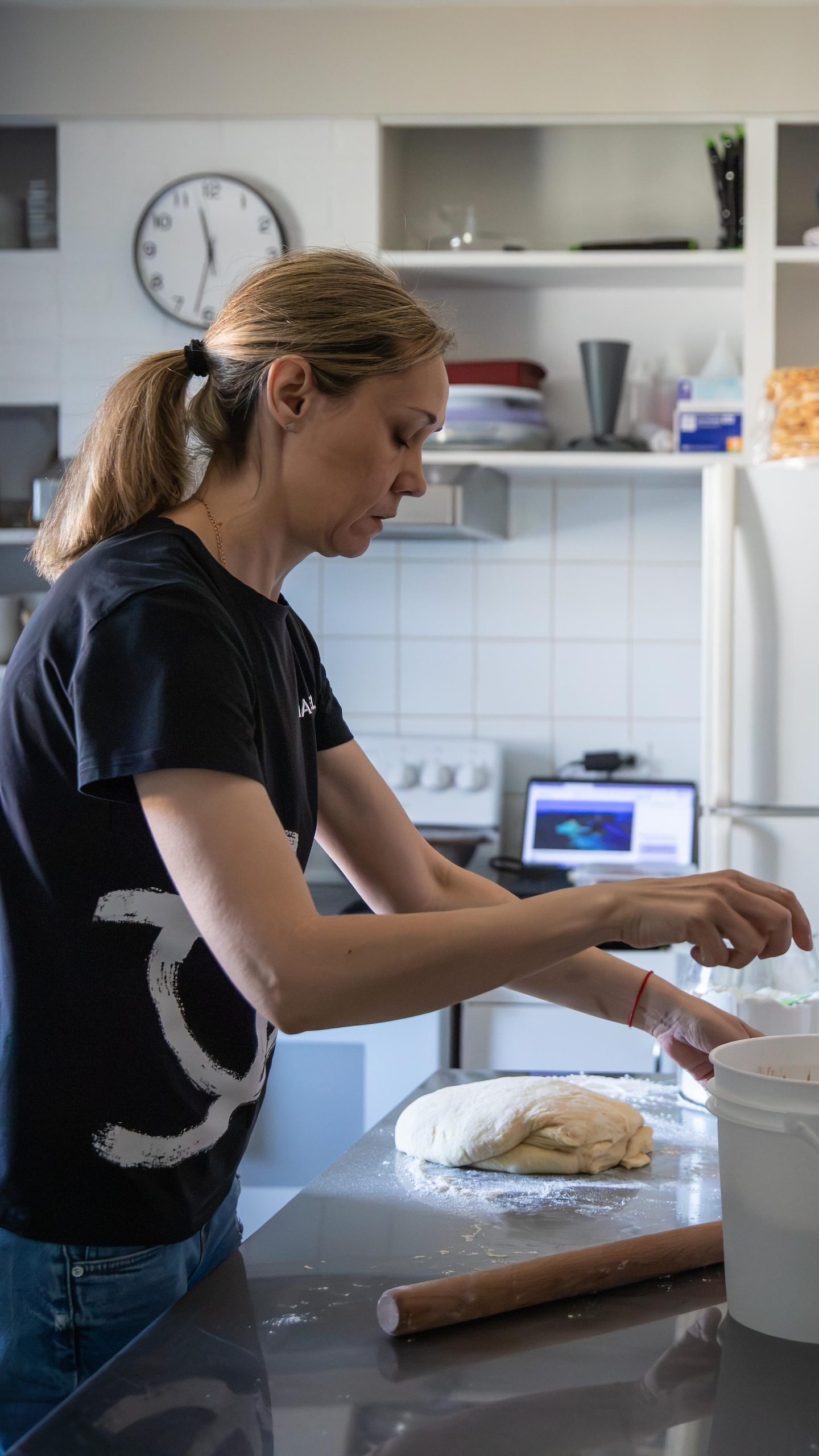 Dans une cuisine, une femme prépare de la pâte au-dessus d'un comptoir sous le regard d'un jeune homme face à elle.