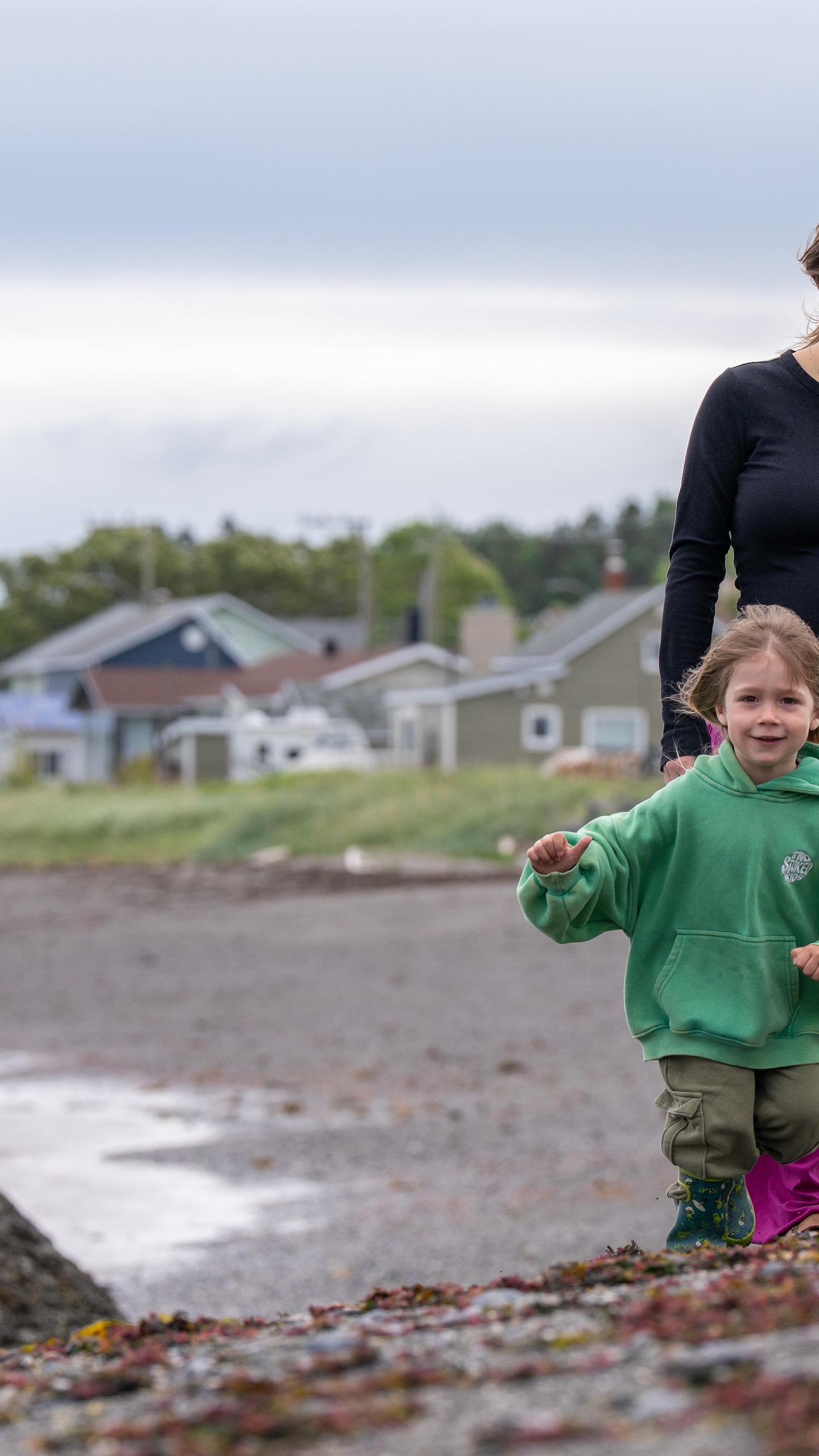 Une femme enceinte marche sur la plage de Saint-Ulric. Son fils de 4 ans court devant elle en souriant.