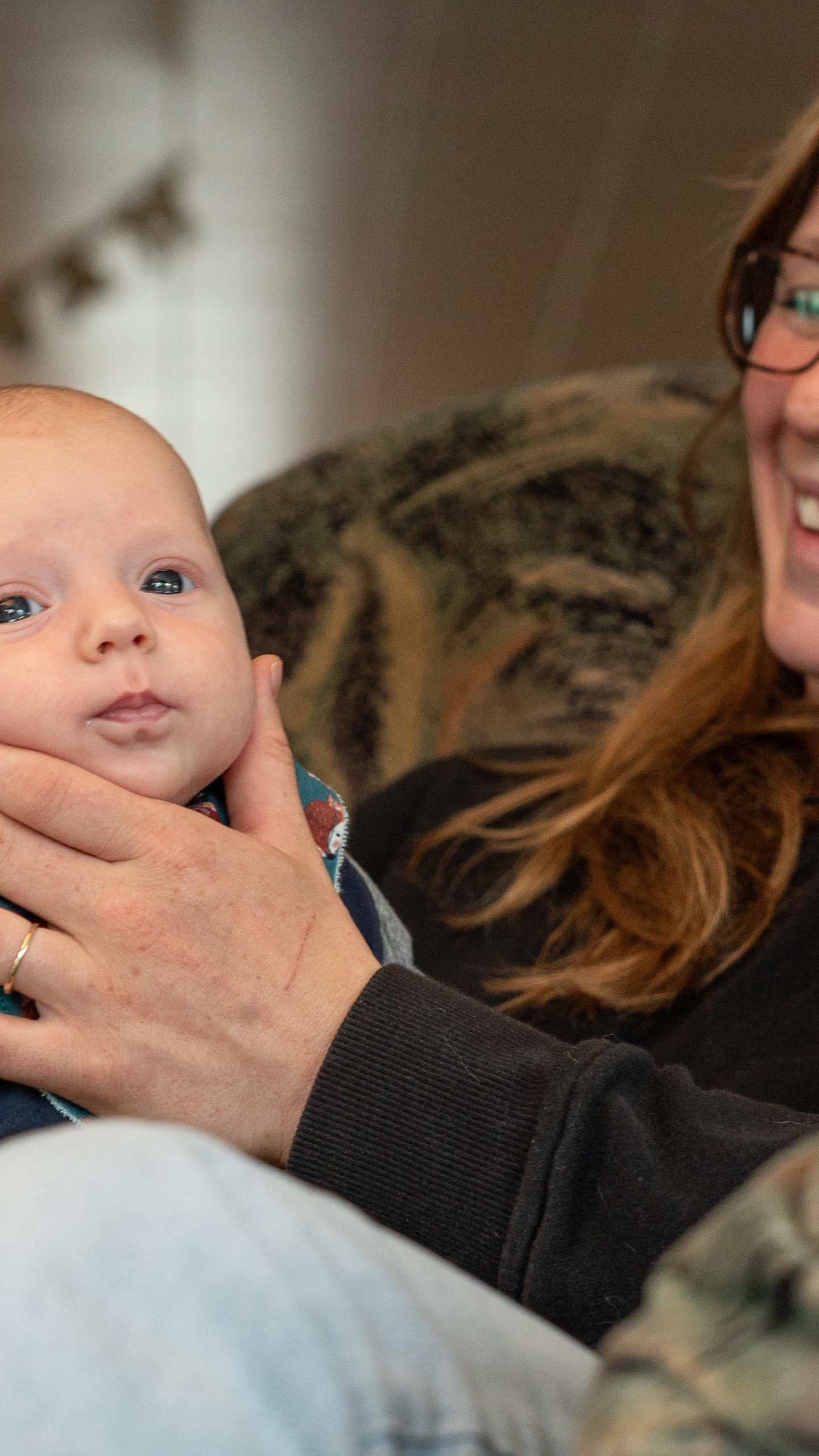 Cloé sourit en tenant la tête de son bébé.