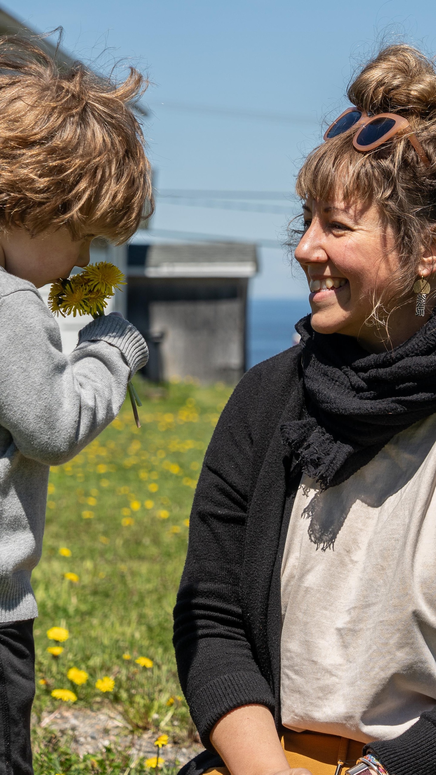 Lysandre sourit en observant Léon sentir un petit bouquet de pissenlits.