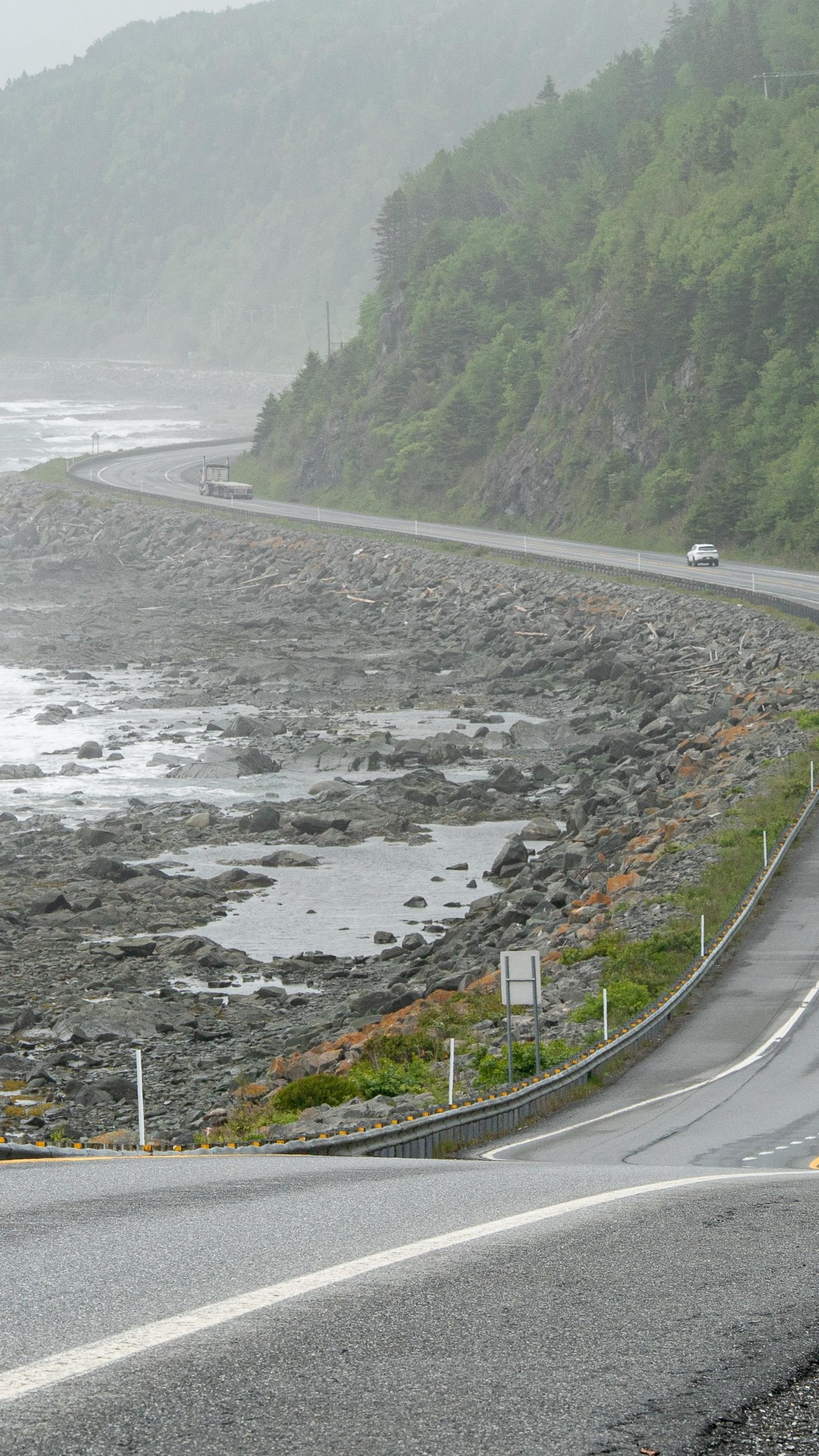 Des voitures circulent sur la route bordée par la mer, en Haute-Gaspésie.