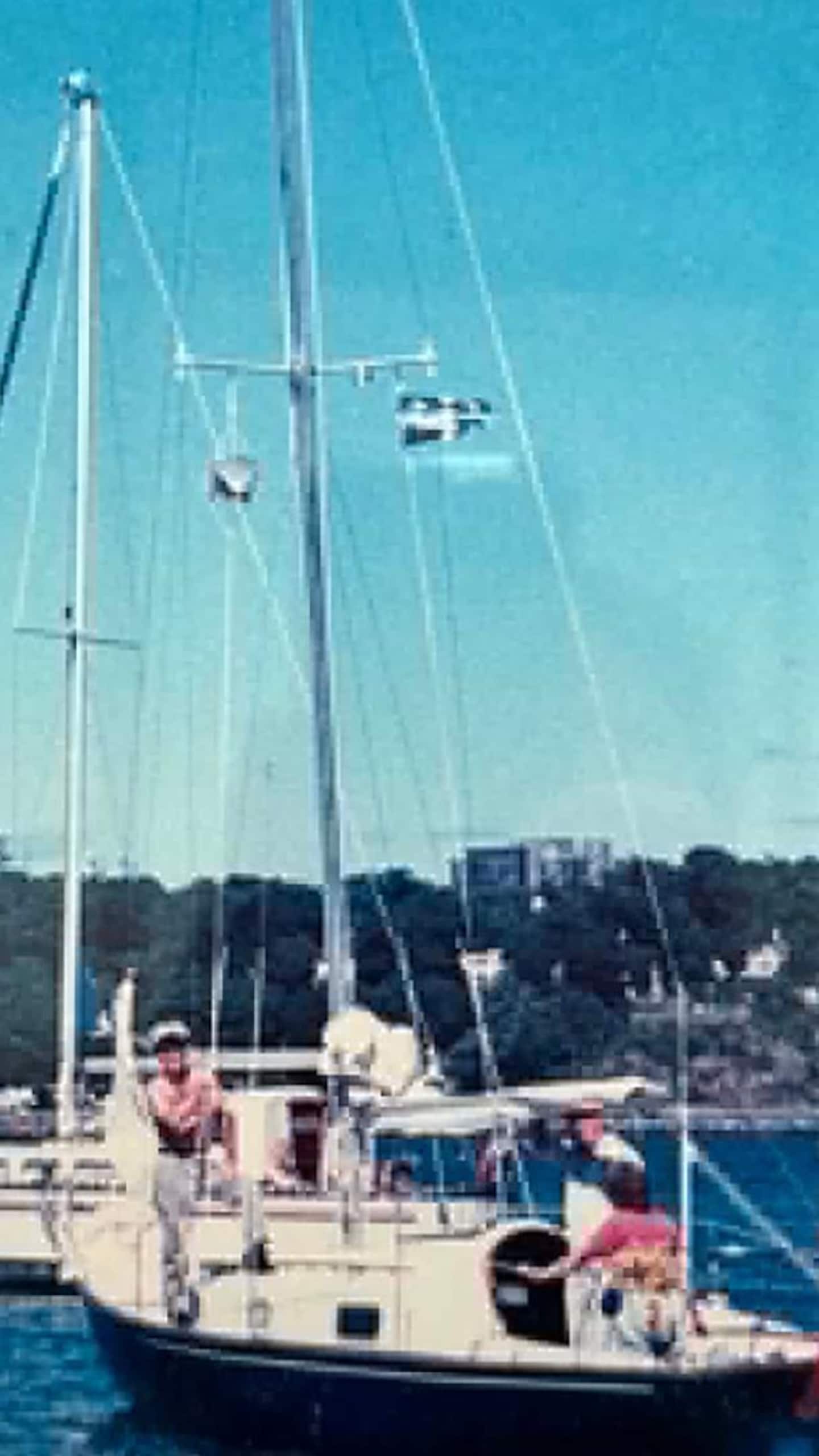 Deux personnes sur un voilier sur l'eau.