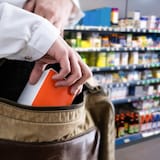 Une personne glisse un produit dans son sac.