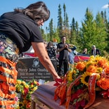 Une femme dépose des fleurs et d'autres herbes sur un cercueil