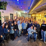Un groupe d’environ 50 personnes réunies pose pour une photo dans un restaurant.