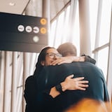 Un couple se serre dans les bras dans un aéroport.