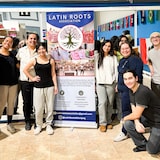 Un groupe de jeunes tient une banderole sur laquelle on peut lire "Latin Roots" (racines latines).