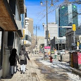 Paysage du centre-ville de Winnipeg avec deux personnes se tournant le dos et marchant dans la rue.