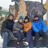 De gauche à droite : Richard Marion, Julie Plourde, Matisse Harvey et Marc-Éric Bouchard posent, souriants, au pied d'une image arborant un renard et un ours, en marge des Jeux d'hiver de l'Arctique de Wood Buffalo, en Alberta, le vendredi 3 février 2023.