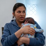 Une femme tient son enfant naissant dans ses bras. 