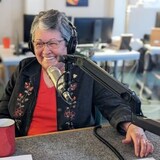 A woman sitting in front of a radio microphone. 