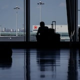 Travellers waiting around in departures at an airport.