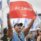 Un homme tient une pancarte « Air Canular ».