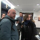 Un homme et une femme entourés de journalistes.