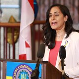La ministre de la Défense, Anita Anand, debout à un podium près d'un drapeau canadien, le 24 mai 2022.