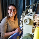 Annie Larocque sourit, assise devant une machine à coudre.
