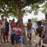 Un groupe de personnes réuni au pied d'un arbre en République dominicaine. 