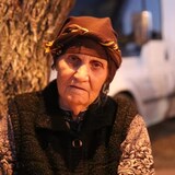 Avansyan Emma, 78, sits wrapped in a blanket at the Kornidzor checkpoint in Armenia waiting for her son, who is making the journey out of Nagorno-Karabakh. (Corinne Seminoff/CBC)