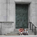 Une famille prend une pause sur les marches du parvis de la Banque du Canada, à Ottawa.