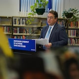 Bernard Drainville devant un lutrin lors de sa conférence de presse presse à l'école secondaire de Rochebelle, à Québec.