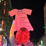 Une femme de dos tient une pancarte.