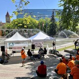 Des personnes sont assises dans un espace extérieur où des tentes ont été installées au centre-ville de Calgary.