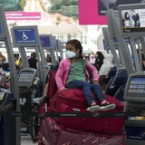 Une fillette attend, assise sur une pile de bagages, à l'aéroport.