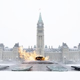 Fotografía de la Llama del Centenario con el edificio del Parlamento detrás

