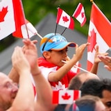 People clap and wave their flags during a Canada Day celebration at LeBreton Flats in Ottawa on July 1, 2022.