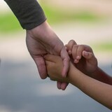 Une mère qui tient son fils par la main.