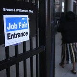 Isang babae papasok sa gate na may karatula na nagsasabing "Job Fair Entrance."